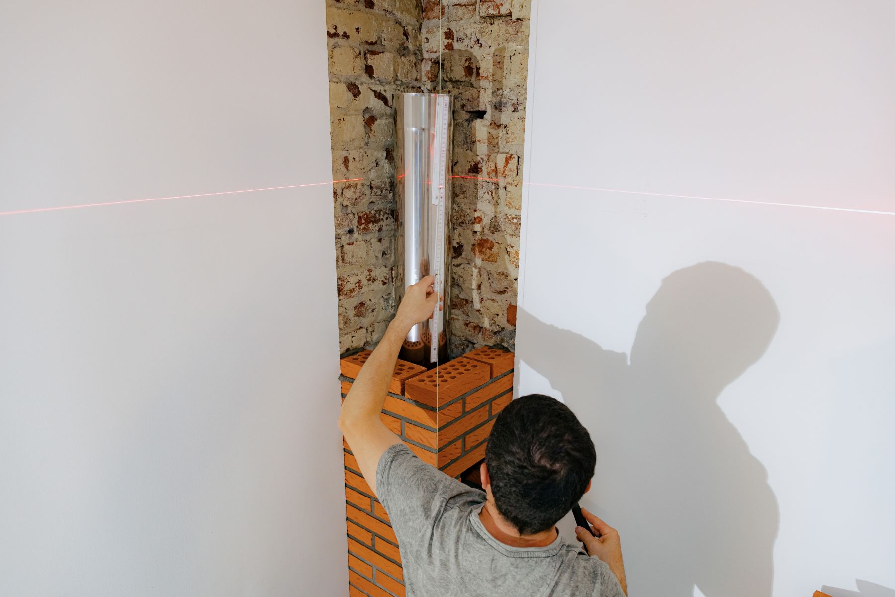 A young man makes brickwork on the chimney of a fireplace.